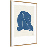 Framed minimalist canvas artwork depicting a blue abstract figure with bent arms and legs on a cream background, signed in bottom right corner.