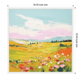 Framed canvas of a colorful meadow landscape with pink flowers in the foreground, green and yellow fields, distant blue hills, and a partly cloudy sky.