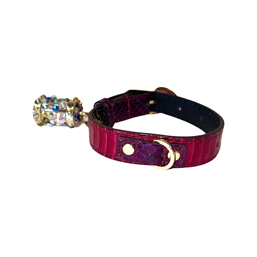 Ruby red and purple snake-patterned collar with a gold D-ring and a jeweled charm attached, shown against a white background.