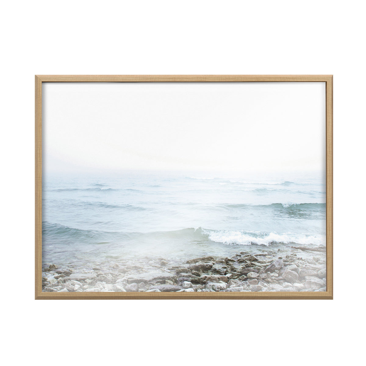 Framed print of a foggy seascape showing gentle waves approaching a rocky shore with soft blues and grays blending into a pale sky.