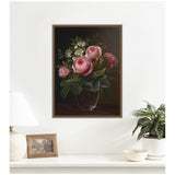 Framed canvas wall art depicting pink roses and white tree anemones arranged in a clear glass vase against a dark background, hanging on a white wall above a modern console.