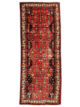 Vintage Persian Hosseinabad runner rug with a red geometric central field, black borders, and floral motifs in cream, yellow, and orange accents.