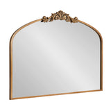 Arched rectangular mirror with a warm gold frame and intricate carved floral ornament centered at the top, against a white background.