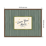 Rectangular framed wall art with dark green and white vertical stripes surrounding a beige central area reading 'Love You More' in black script, accented by small gold stars and a scalloped olive border.
