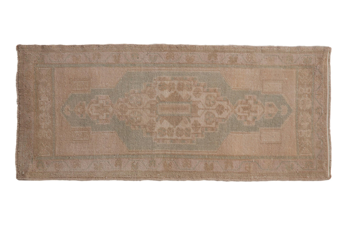 Elongated center medallion detail on 1.5x3.5 vintage distressed Oushak rug with floral motifs in soft antique ivory and seafoam green tones