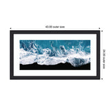 Minimalist aerial view of ocean waves crashing onto a solid black beach, framed in a black rectangular frame with white matting, 43 by 24 inches outer size.
