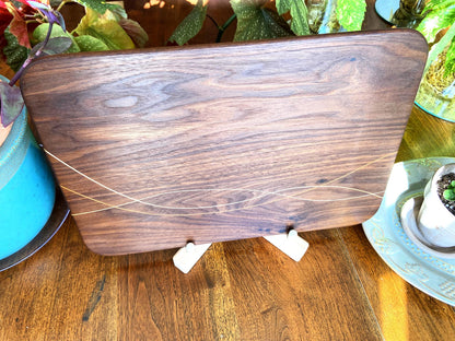 Peruvian Walnut charcuterie board with Maple and Cherry wood inlay on a table
