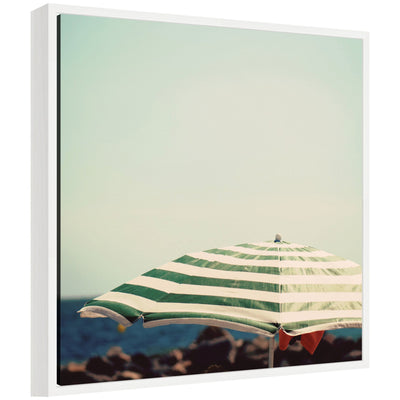 Framed canvas wall art titled 'Under the Umbrella' by Laura Evans showing a coastal scene in a white frame