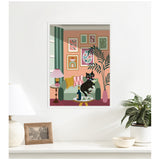 Framed illustration of a black cat sitting on a green armchair surrounded by colorful framed art, a pink lamp, and a large leafy plant on a peach wall.