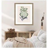 Minimalist green line drawing of a vase with flowers, titled 'Les Fleurs,' framed and hung above a cozy bed with neutral-toned linens and a wooden cabinet.