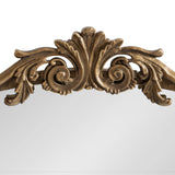 Top arch of a traditional mirror frame with ornate gold leaf detailing featuring symmetrical scrolls and a central floral motif.
