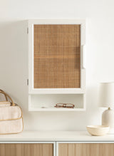 White rectangular wall cabinet with a woven rattan door panel and an open cubby below, shown mounted on a white wall above a light wood console.