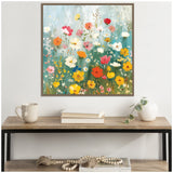Framed canvas painting of colorful wildflowers in shades of red, yellow, pink, and white against a soft blue-green background, hung above a wooden console table.