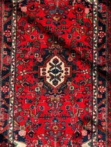 Hand-knotted Persian Hamadan wool rug in rich red with intricate floral motifs and a central diamond medallion bordered by navy and ivory patterns.