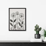Black and white botanical linocut print with stylized flowers and leaves in a simple black frame hanging above a black wooden surface with green potted plants and white books.