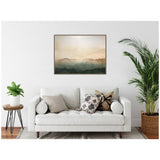 Abstract horizontal canvas featuring soft layers of green, beige, and brown tones resembling misty mountains, hung above a white sofa with patterned pillows in a minimalistic living room.