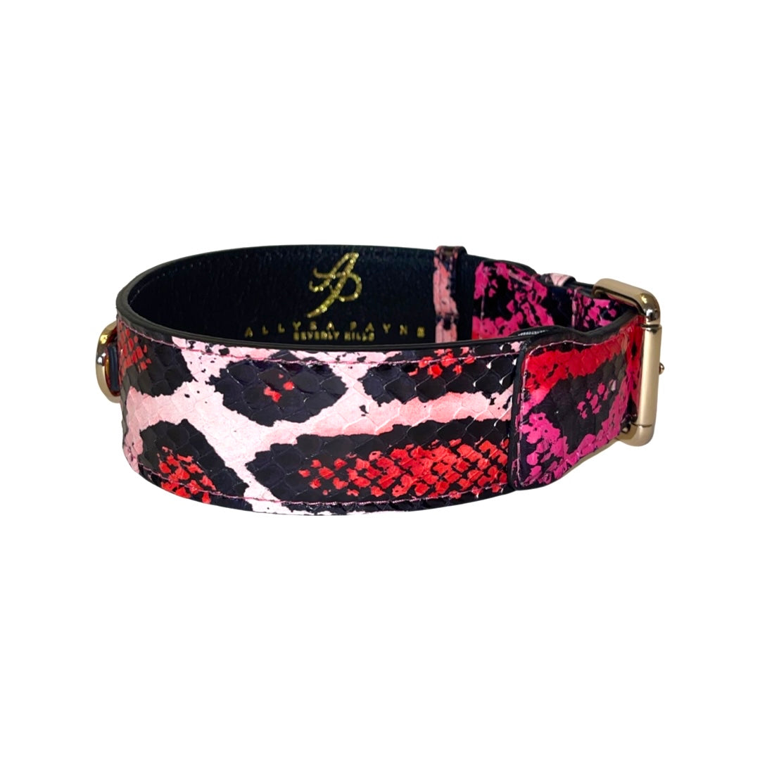 Dog collar with fuchsia, light pink, red, and black snake print pattern and gold metal buckle, shown in side view against white background.