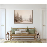 Framed canvas of a winter forest landscape with softly blurred neutral brown and beige trees above a wooden bench with green and white pillows in a minimalist room.