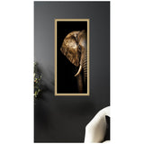 Close-up of a golden elephant head with intricate mandala patterns on its ear and trunk against a black background, framed and hanging on a dark gray wall.