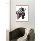 Framed canvas print of a stylized zebra portrait with black and beige stripes, adorned with white flowers and green foliage, hanging above an olive green armchair with a knitted throw.
