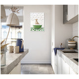 Minimal kitchen with light gray countertops, white cabinets, and a framed canvas showing a cheetah in a green bathtub against patterned wallpaper, centered on the far wall.