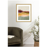 Abstract landscape painting with layered horizontal bands of burgundy, mustard yellow, peach, and green hues in a light wood frame above a dark olive armchair and potted olive tree on white wall.