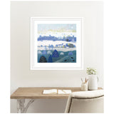 Framed painting 'Winter Dales' by Giuliana Lazzerini, featuring layered blue and white snowy hills with stylized trees and houses under a pale sky, hanging above a rustic wooden desk.