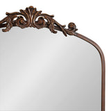 Arch-shaped mirror with a dark brown carved wood frame featuring intricate scroll and leaf designs at the top center.