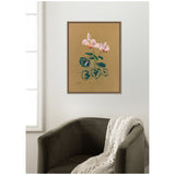 Framed canvas print of 1916 Odilon Redon's Cyclamen painting featuring pink flowers with green leaves on a tan background, hanging above a dark green armchair with a cream knit throw.