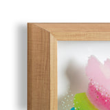 Close-up of a light wooden frame corner surrounding abstract art with soft pink and green colors and white dot accents on a white background
