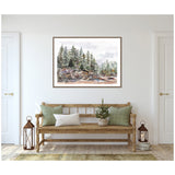 Framed painting of pine trees on rocky terrain with muted greens and browns, hanging on a white wall above a wooden bench with green and white pillows and decorative lanterns.