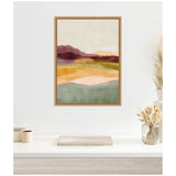 Abstract landscape painting with layered hills in mauve and peach tones over patches of green and blue, framed and hung on a neutral wall above a minimalist desk