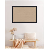 Rectangular cork pinboard with a black scallop-themed printed border, hanging centered on a light-colored wall above a wooden bench with beige pillows and a light throw.