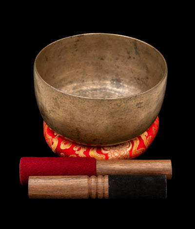 Antique Thadobati Singing Bowl F 170Hz 7 1/4" A16089 showing its golden brown patina and textured surface with accompanying silk-brocade ring and two mallets.