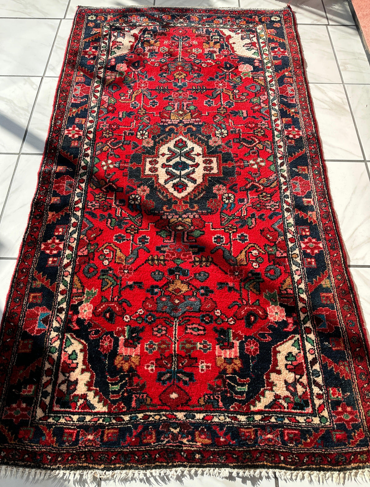 Hand-knotted Persian Hamadan wool rug with a red field featuring central geometric medallions and intricate floral patterns in navy blue, ivory, and pink.