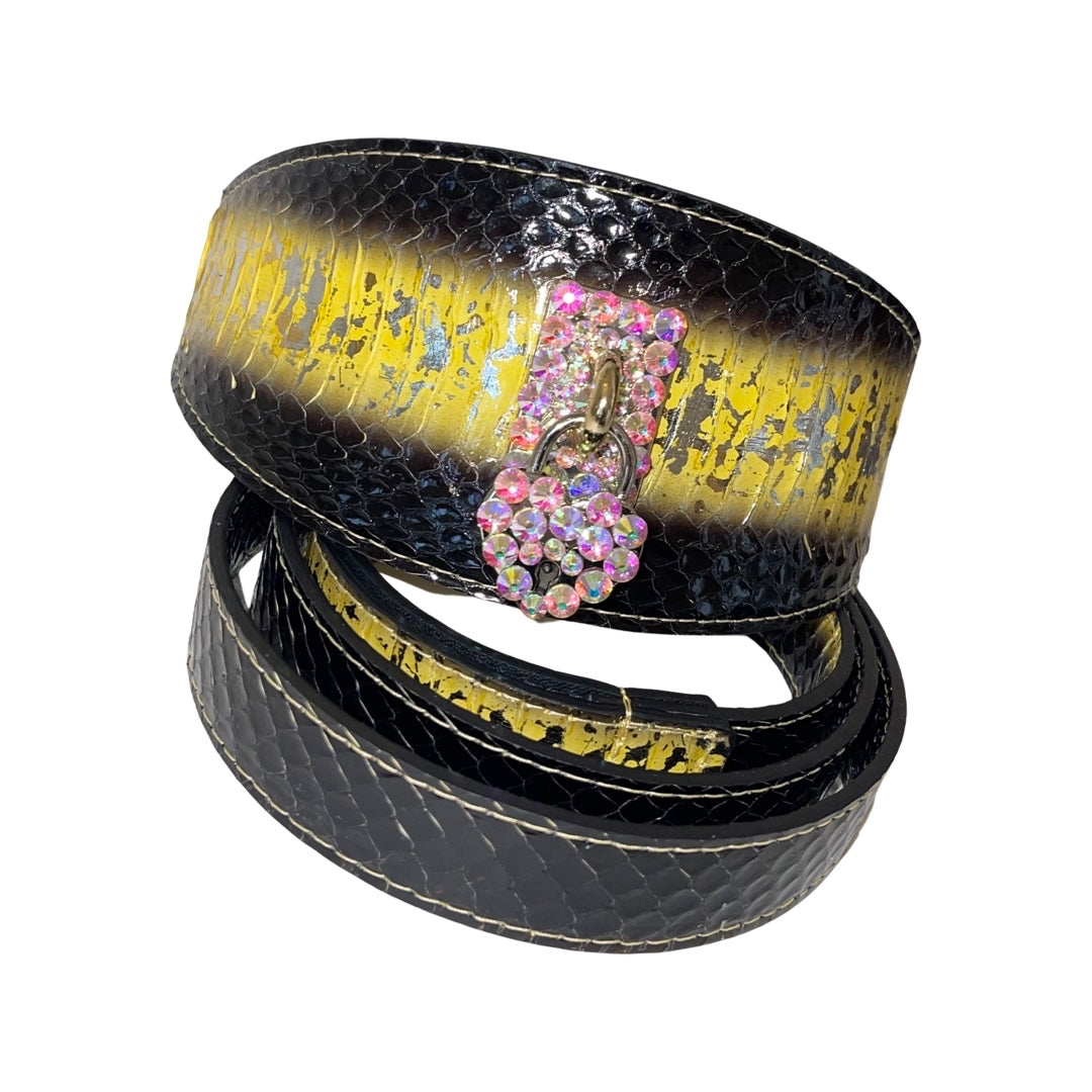 Black snake-patterned collar with a wide yellow-gold metallic stripe and a pink Swarovski crystal heart-shaped latch, displayed coiled on white background.