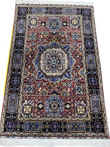 Rectangular hand-knotted Afghani rug with central medallion in blue and brown, surrounded by intricate floral and geometric motifs with a dark blue border and white fringes.