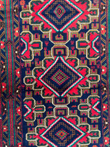 Hand-knotted Afghani Baluch wool rug with three large navy and red diamond medallions on a dark blue background, featuring intricate geometric patterns in red, green, and brown.