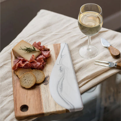 Wooden Cheese Charcuterie Serving Board with cured meats, bread, and a glass of white wine on a textured surface.