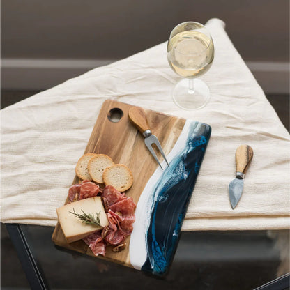 Wooden Cheese Charcuterie Serving Board with cured meats, cheese, and bread on a white cloth with a glass of white wine.