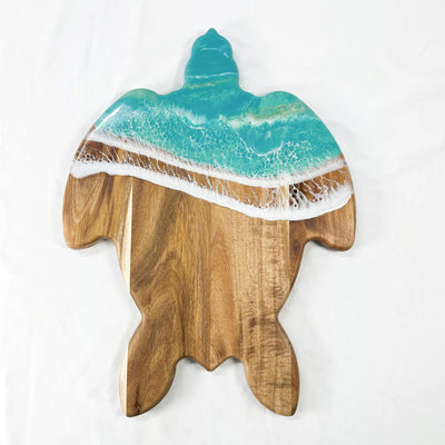 Handcrafted sea turtle-shaped charcuterie board with acacia wood and blue resin accents, topped with fruit and cheese.
