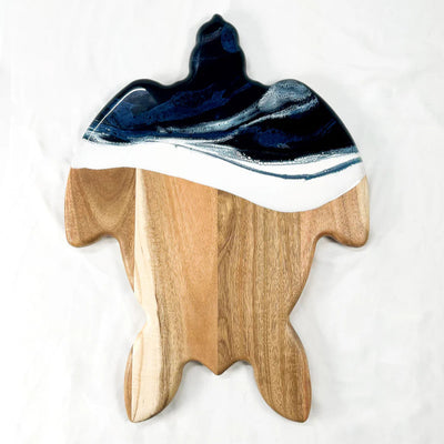 Handcrafted sea turtle-shaped charcuterie board with acacia wood and blue resin accents, topped with fruit and cheese.