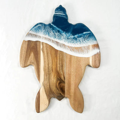 Handcrafted sea turtle-shaped charcuterie board with acacia wood and blue resin accents, topped with fruit and cheese.