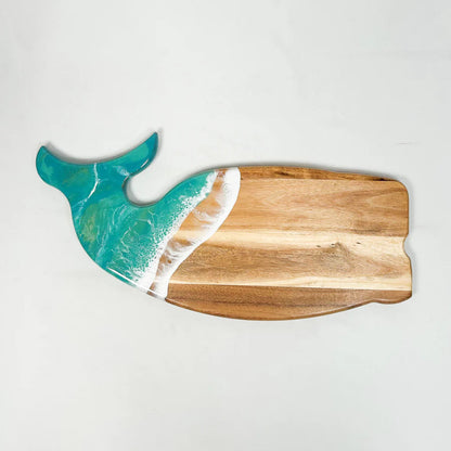 Wooden whale shaped charcuterie board shaped like a whale with a teal and white design on a light gray background