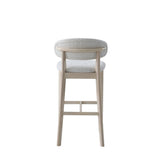 Mid-century modern bar stool with light wood frame and curved upholstered backrest in soft white boucle fabric, shown from the rear