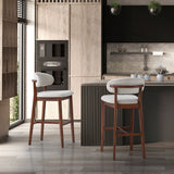 Two mid-century modern bar stools with curved white upholstered backs and seats, and warm wood frames, positioned beside a kitchen island with ribbed dark panels.