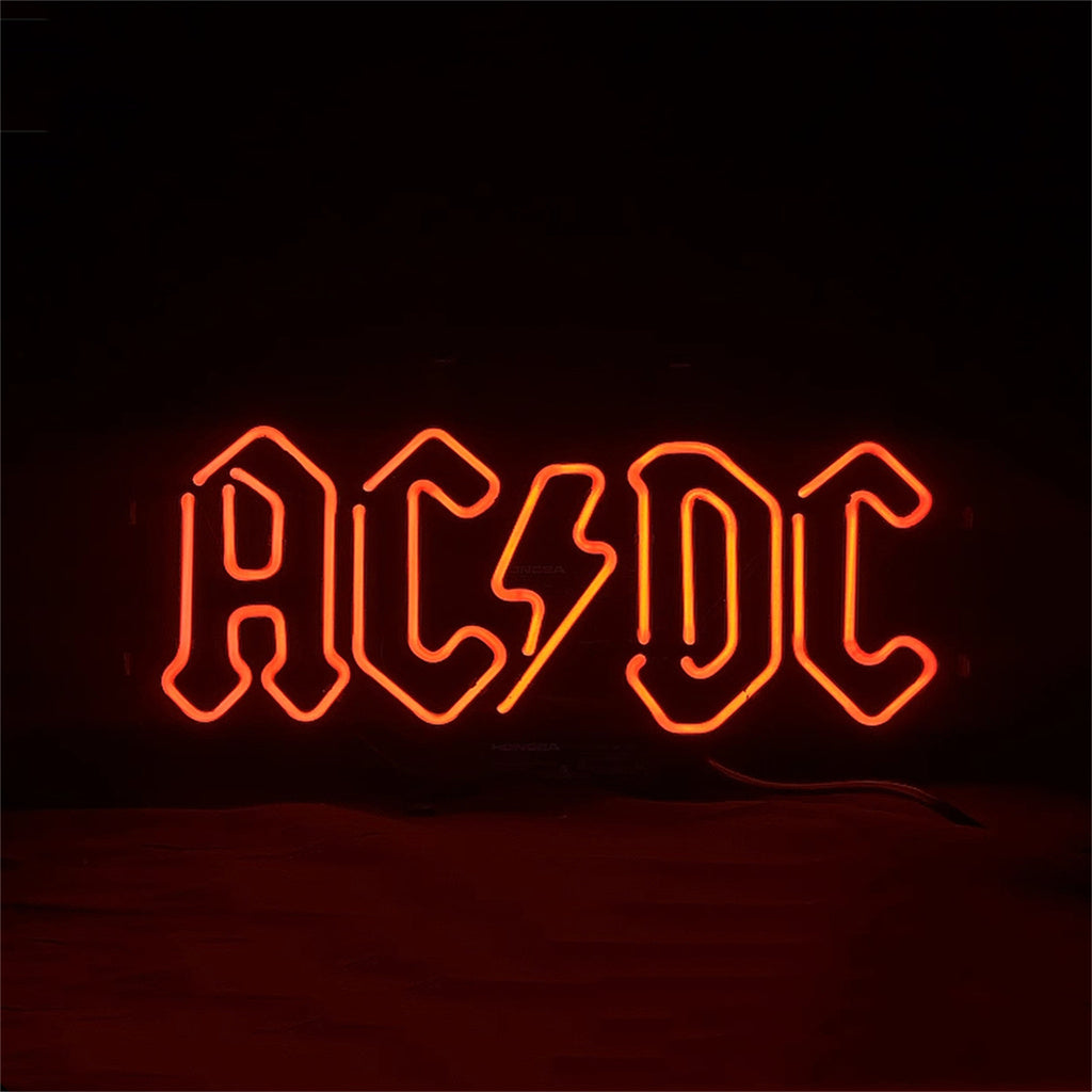 Red neon sign displaying the band name AC/DC with a lightning bolt symbol in place of the slash, set against a dark background.