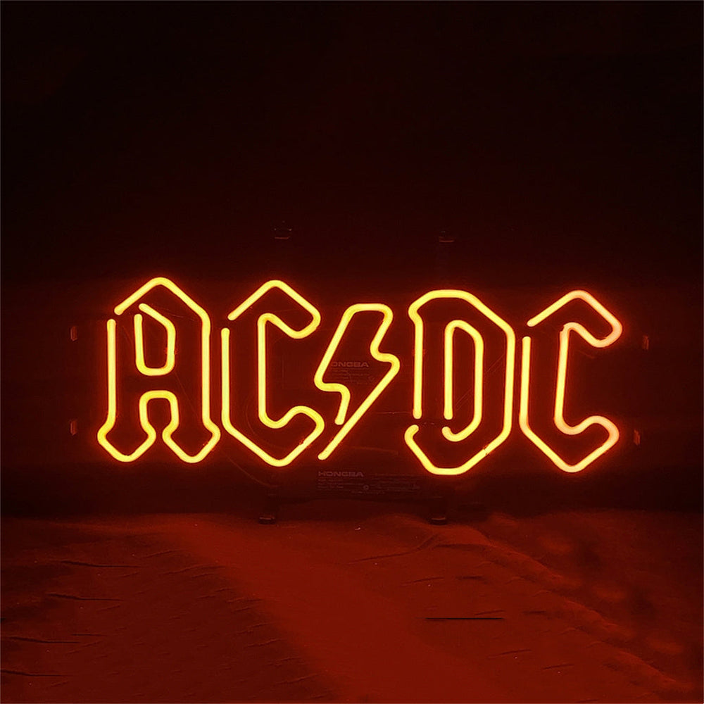 AD DC Neon Signs glowing with vibrant blue and pink neon illumination on a metal grid backing.