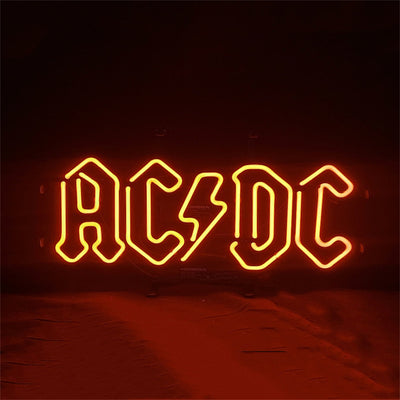 AD DC Neon Signs glowing with vibrant blue and pink neon illumination on a metal grid backing.