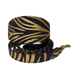 Black and gold zebra print Italian leather dog collar and matching leash with gold hardware, displayed coiled on a white background.